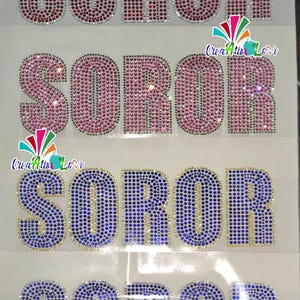 May include: Four rhinestone-studded "SOROR" designs in red, pink, and blue. The letters are outlined in gold. The designs are on a white background. The image also includes a colorful logo with the text "Creatin Love".