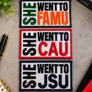 May include: Three rectangular embroidered patches with white backgrounds and black borders. The top patch features green text reading SHE WENT TO and orange text reading FAMU. The middle patch has black text SHE WENT TO and red text CAU. The bottom patch has black text SHE WENT TO and navy blue text JSU.