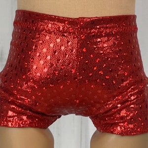 May include: Red sparkly shorts with a dotted pattern. The shorts are made of a shiny fabric and have a stretchy waistband.