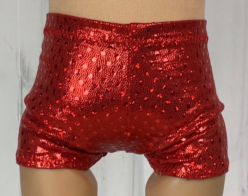 May include: Red sparkly shorts with a dotted pattern. The shorts are made of a shiny fabric and have a stretchy waistband.