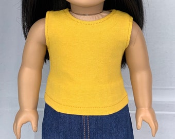 May include: A sleeveless yellow tank top for a doll. The tank top has a round neckline and is made of a soft, stretchy fabric.