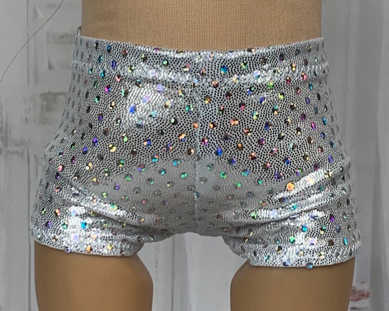May include: Silver shorts with iridescent polka dots. The shorts are made of a shiny, stretchy fabric.