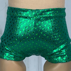 May include: Green shiny shorts with a polka dot pattern. The shorts are made of a stretchy fabric and have a high waist.