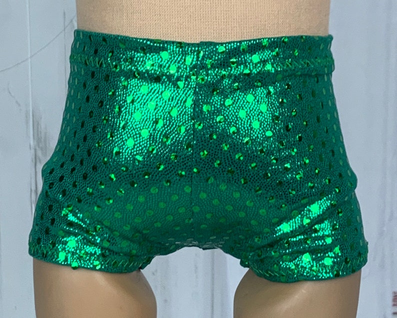 May include: Green shiny shorts with a polka dot pattern. The shorts are made of a stretchy fabric and have a high waist.