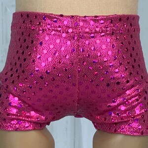 May include: Pink shiny shorts with a polka dot pattern. The shorts are made of a stretchy material and have a high waist.
