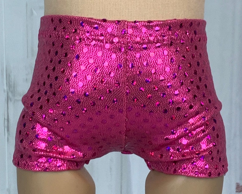 May include: Pink shiny shorts with a polka dot pattern. The shorts are made of a stretchy material and have a high waist.