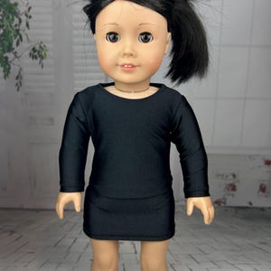 May include: A black long-sleeved dress with a round neckline, worn by a doll with black hair.