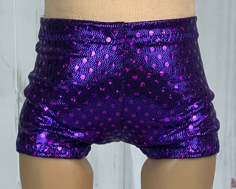 May include: Purple shorts with a shiny, iridescent finish and a polka dot pattern.