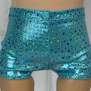 May include: Teal blue shorts with a sparkly, iridescent finish. The shorts have a small, polka dot pattern.