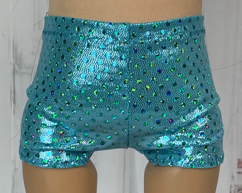 May include: Teal blue shorts with a sparkly, iridescent finish. The shorts have a small, polka dot pattern.