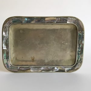 Puede incluir: Una bandeja de plata con un borde decorativo hecho de azulejos de nácar iridiscente.