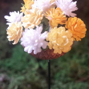 Dollhouse/fairy garden planter with yellow and white flowers.