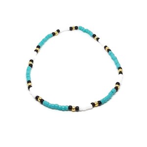 May include: A turquoise, white, and black beaded bracelet with gold accents.
