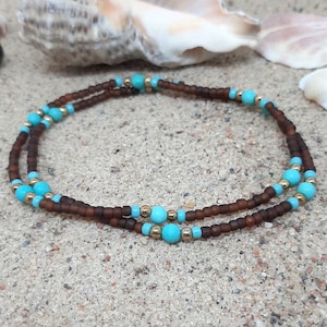 May include: A brown and turquoise beaded bracelet with gold accents. The bracelet is made of small, round beads and is designed to be worn on the wrist.