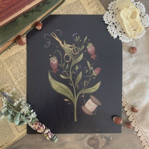 May include: A black and white illustration of a plant with pink flowers, a gold pair of scissors, and a spool of thread. The illustration is on a black background.