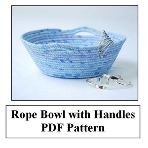 May include: A blue rope bowl with handles. The bowl has a light blue and white pattern. The text "Rope Bowl with Handles PDF Pattern" is below the image.