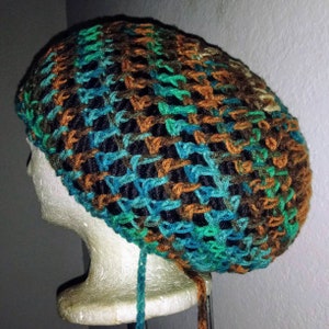 May include: A crocheted beanie hat with a brown, green, and blue color pattern. The hat is on a white mannequin head.