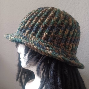 May include: A crocheted bucket hat with a camouflage pattern in shades of brown, green, and blue.