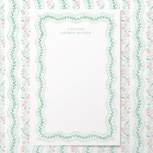 May include: A white card with a green leafy border and the text "A note from LAUREN HUTTON". The background is a white and green floral pattern.