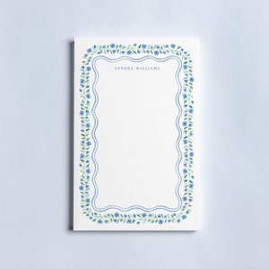 May include: A white notepad with a blue and green floral border. The notepad has the name "SANDRA WILLIAMS" printed at the top.
