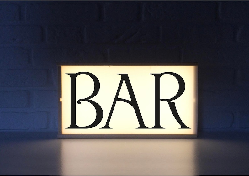 May include: A white light-up sign with the word "BAR" in black lettering.