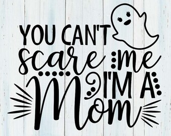 Può includere: Design grafico nero su sfondo in legno chiaro. Il testo recita "YOU CAN'T scare me I'M A Mom" con un'illustrazione di un fantasma. Sotto, i tipi di file: SVG/DXF/PNG/EPS.