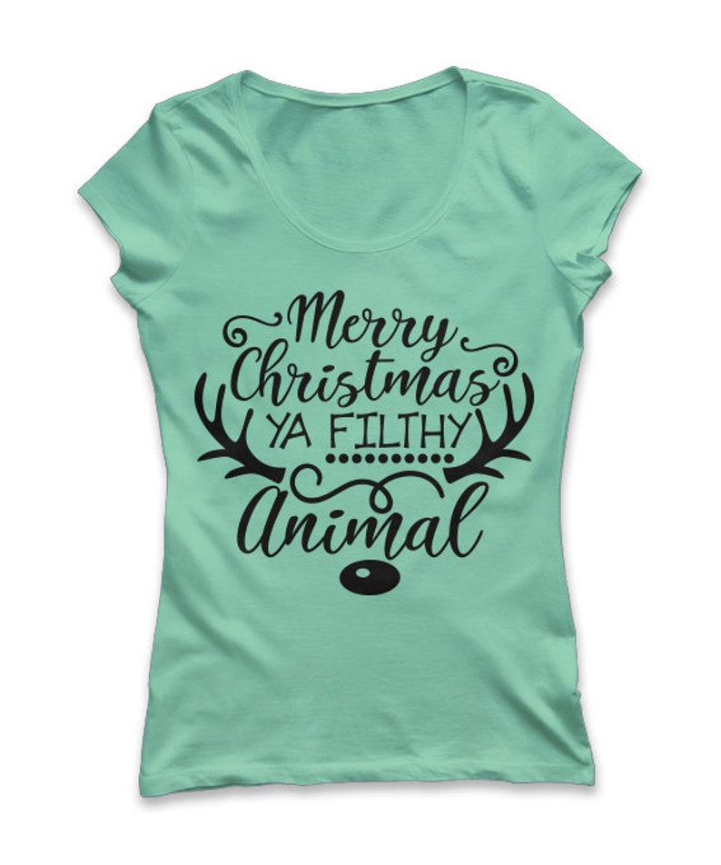 May include: A light green t-shirt with a scoop neck. The shirt features the text "Merry Christmas Ya Filthy Animal" in black script, with reindeer antlers and a small dot design. The word "Animal" is in a larger font.