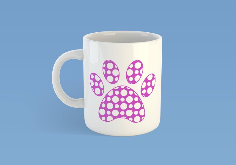 May include: A white ceramic mug featuring a large, magenta-colored paw print graphic on the front. The paw print design is filled with a pattern of small, white circular dots throughout the entire shape of the animal paw print.