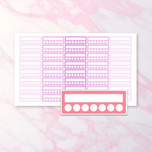 May include: A sheet of pink and white planner stickers with a marble background. The stickers have a rectangular design with a series of dots and rectangles. A separate sticker with a similar design is in the foreground.