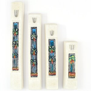 May include: Set of four white ceramic mezuzah cases with a silver shamash and a colorful mosaic design of palm trees and flowers.