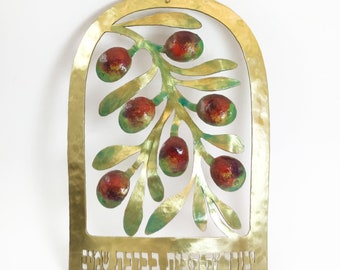 May include: A gold metal wall hanging with a cutout design of an olive branch with red olives. The Hebrew text "ברוך הבא הביתה" is inscribed at the bottom.