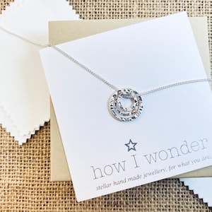 May include: Silver necklace with a layered circle pendant. The necklace comes in a box with a white card that reads "how I wonder stellar hand made jewellery, for what you are."