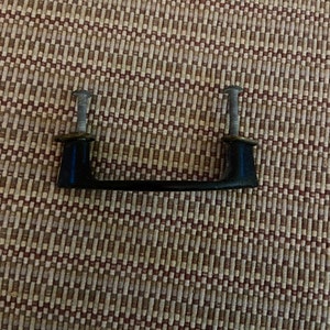 May include: Black cabinet hardware with a simple, rectangular design. The handle has two silver screws on each end.