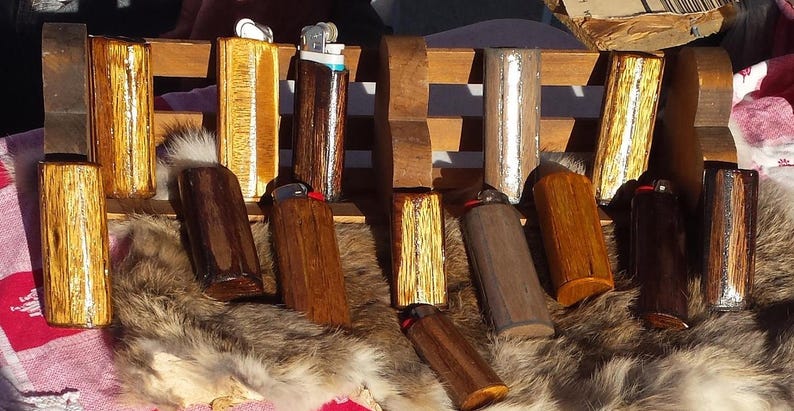Puede incluir: Una colecci&oacute;n de encendedores de madera con varios patrones de veta de madera y acabados. Algunos encendedores tienen un acabado met&aacute;lico plateado o dorado. Los encendedores est&aacute;n dispuestos sobre una superficie de piel.