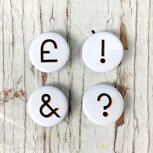 May include: Four white round buttons with black symbols. The buttons feature a pound sign, an exclamation point, an ampersand, and a question mark.