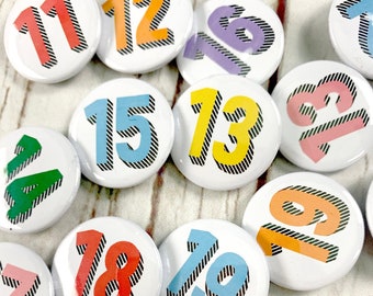 Birthday pin badges in a rainbow of colours. Number pin's 11, 12, 13, 14, 15, 16, 17, 18, 19. Teenager.  25mm/38mm. 'Bradford Buzz' font.