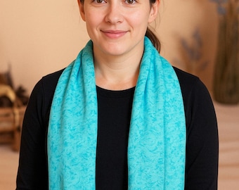 May include: A woman wearing a black long-sleeved shirt with a turquoise patterned scarf around her neck.