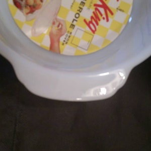 K&ouml;nnte beinhalten: Eine wei&szlig;e Keramik-Auflaufform mit einem gelben und roten Etikett, auf dem "King Size Casserole" steht.