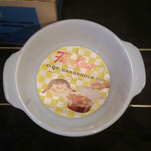 K&ouml;nnte beinhalten: Eine wei&szlig;e 1,5-Liter-Auflaufform mit goldenen Griffen und einem gelben und wei&szlig;en Etikett mit der Aufschrift "Fire King Ovenware 1 1/2 Qt. Casserole  with  Snap-Tite Cover"