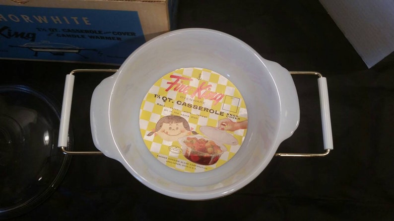 K&ouml;nnte beinhalten: Eine wei&szlig;e 1,5-Liter-Auflaufform mit goldenen Griffen und einem gelben und wei&szlig;en Etikett mit der Aufschrift "Fire King Ovenware 1 1/2 Qt. Casserole  with  Snap-Tite Cover"