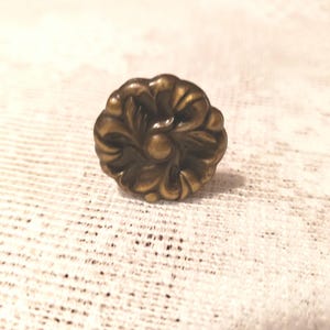 May include: A bronze-colored, floral-shaped cabinet knob. The knob features a detailed, symmetrical design with curved leaves radiating from a central point. The hardware is likely made of metal.