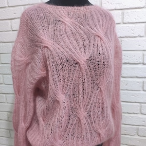 May include: A pale pink, lightweight knitted sweater with a loose fit and a cable knit pattern.