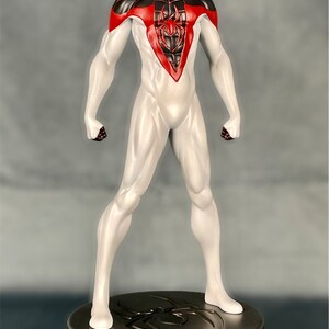 May include: A white and black action figure of Spider-Man with red accents. The figure is standing on a circular base with a spider web design.