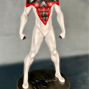 May include: A white and black Spider-Man action figure with red accents. The figure is standing on a black and silver base with a spider logo.