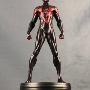 May include: A black and red action figure of Spider-Man, standing on a silver base. The figure is posed with arms outstretched and fists clenched.