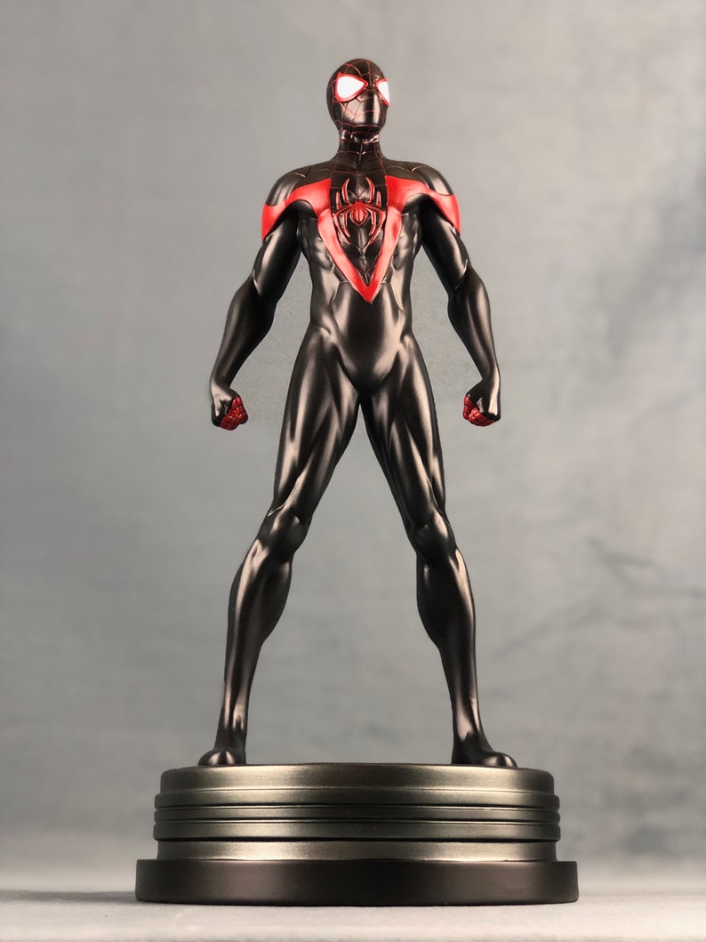 May include: A black and red action figure of Spider-Man, standing on a silver base. The figure is posed with arms outstretched and fists clenched.