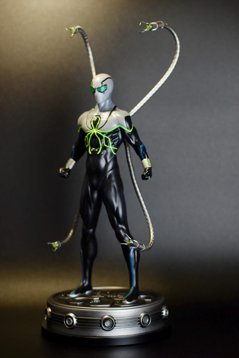 Puede incluir: Una figura de acci&oacute;n negra y verde de un superh&eacute;roe con cuatro brazos mec&aacute;nicos. La figura est&aacute; de pie sobre una base plateada con un dise&ntilde;o circular.