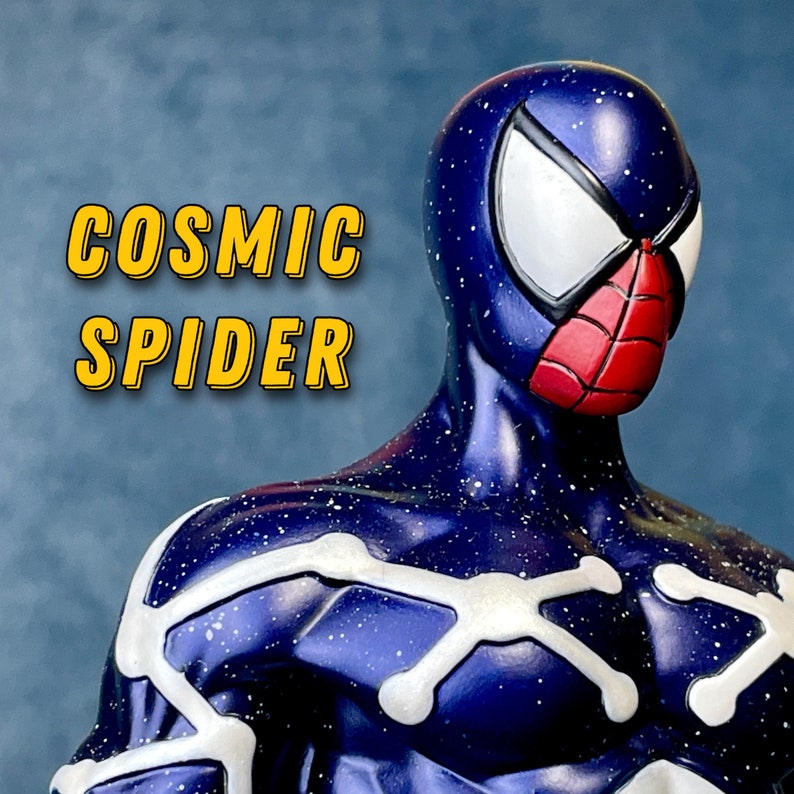Puede incluir: Una figura de Spider-Man c&oacute;smico azul y blanco con un s&iacute;mbolo de ara&ntilde;a rojo en la m&aacute;scara. La figura tiene un patr&oacute;n de cielo estrellado en el traje.