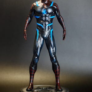 May include: A black and blue superhero figurine with red accents, standing on a circular base. The figure has a detailed costume with a spider emblem on the chest and a web-like pattern on the head and limbs. The figurine is approximately 12 inches tall.