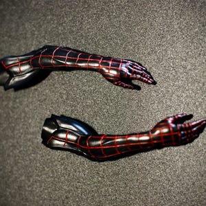 May include: Two black and red action figure arms, featuring a webbed pattern. The arms are posed with open hands, showcasing the intricate design and detail. The figure arms are set against a dark gray background.